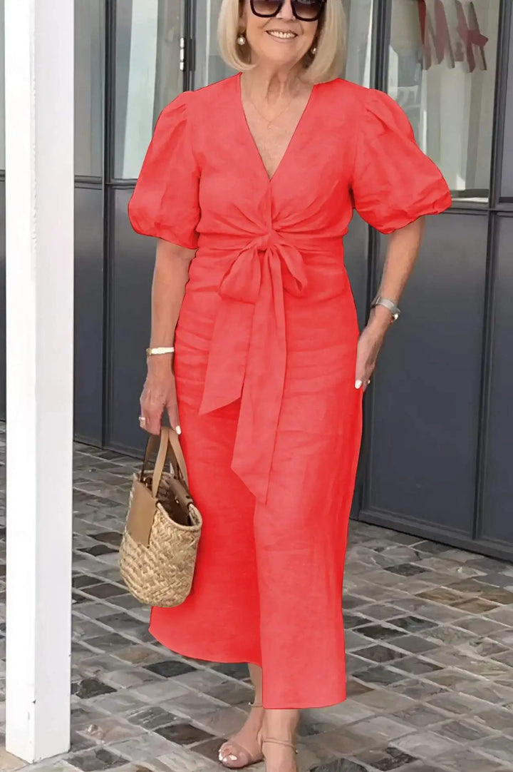 Woman wearing the Christina bow-front midi dress with puff sleeves at a garden party.