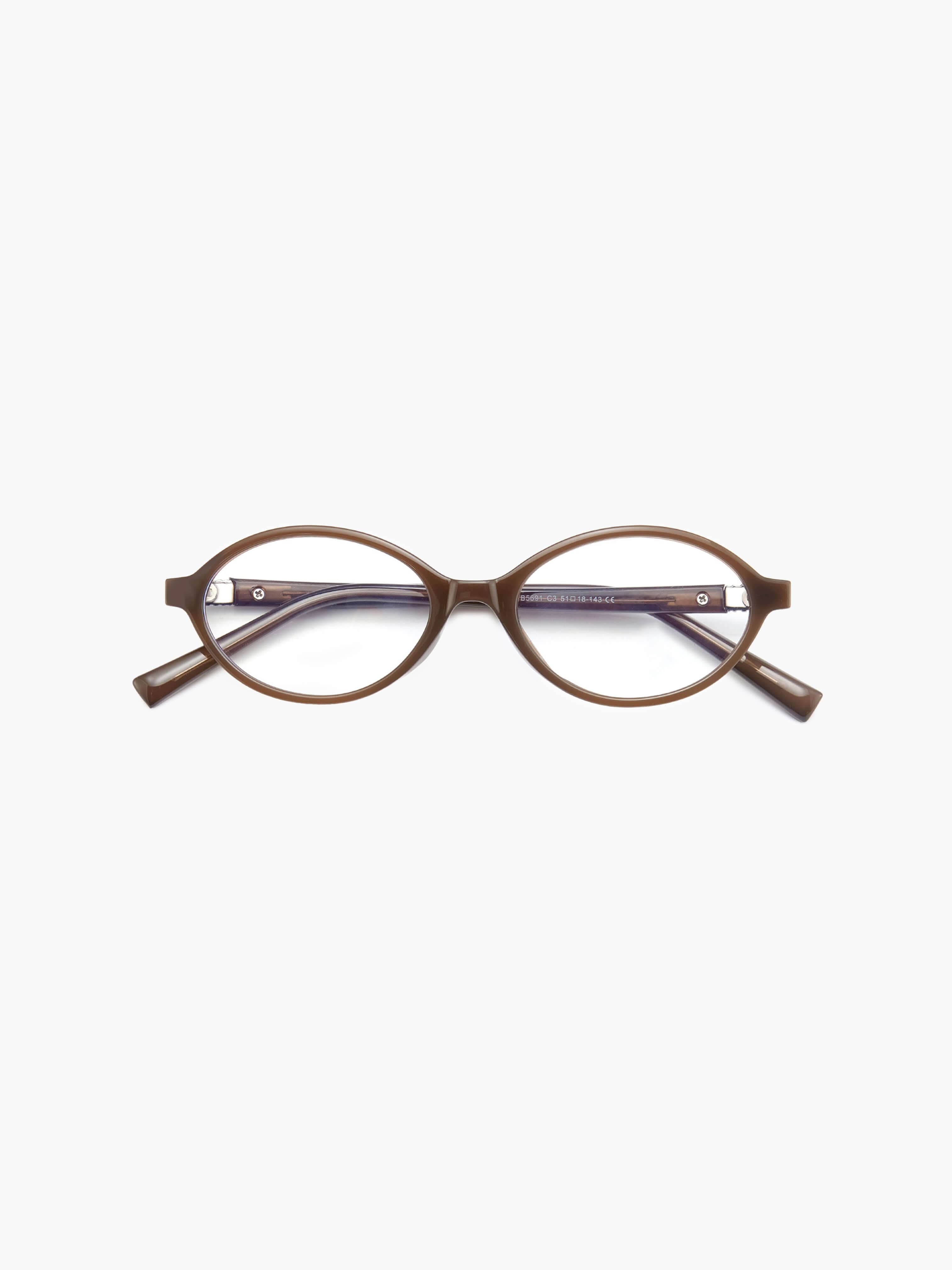 A woman wearing minimalist blue-light reading glasses while relaxing at home.