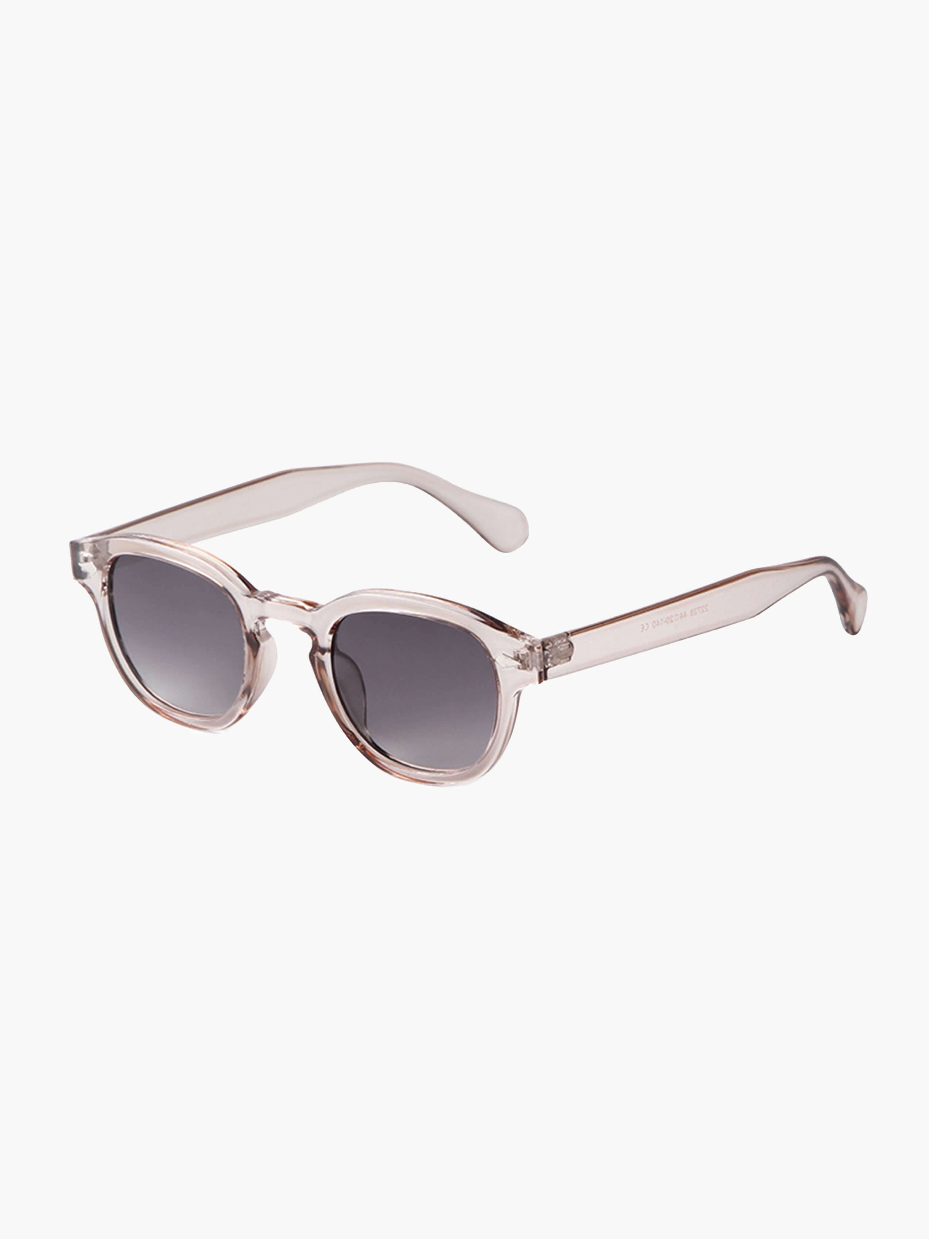 A woman wearing chic round-frame sunglasses on a city walk.