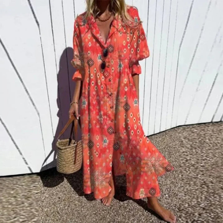 Woman wearing the Gail™ leaf print maxi dress with a button front, walking along the coast in a light breeze.
