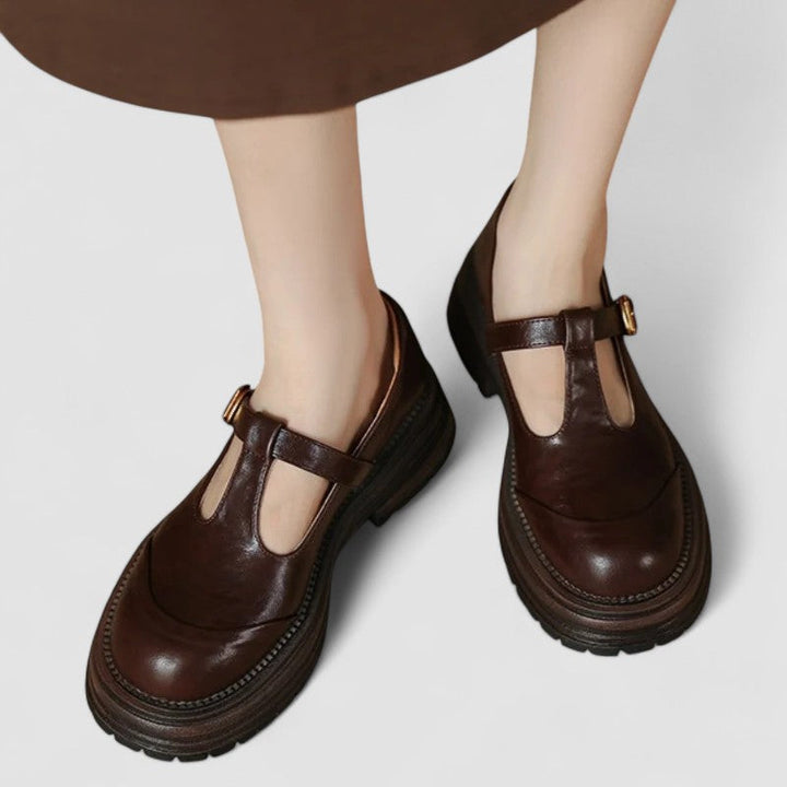 Woman wearing brown Mary Stacey comfort shoes with a T-strap, standing on a city footpath.