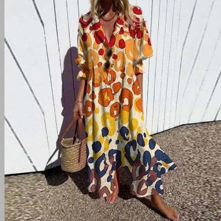 Woman wearing the Gail™ leaf print maxi dress with a button front, walking along the coast in a light breeze.