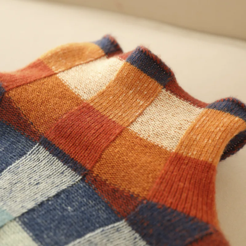 A woman wearing a colourful retro check sweater, relaxed and cosy on a cool fall morning.