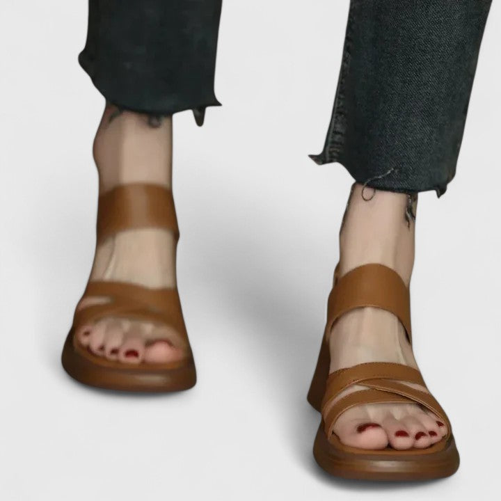A woman wearing elegant cross-strap sandals with a summer dress, looking graceful and comfortable.