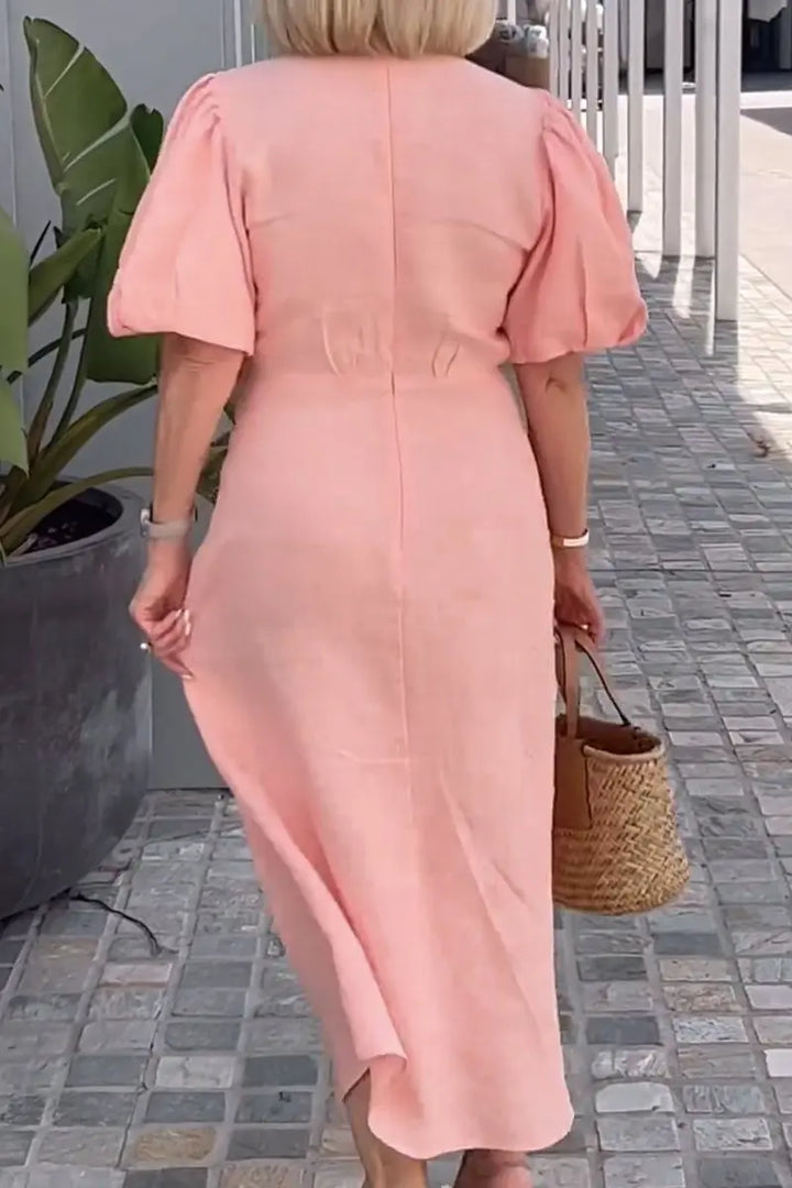Woman wearing the Christina bow-front midi dress with puff sleeves at a garden party.