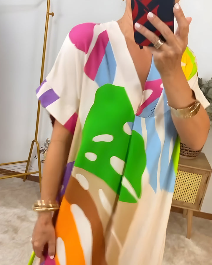A woman wearing a colourful abstract print dress with a V-neckline and short sleeves.