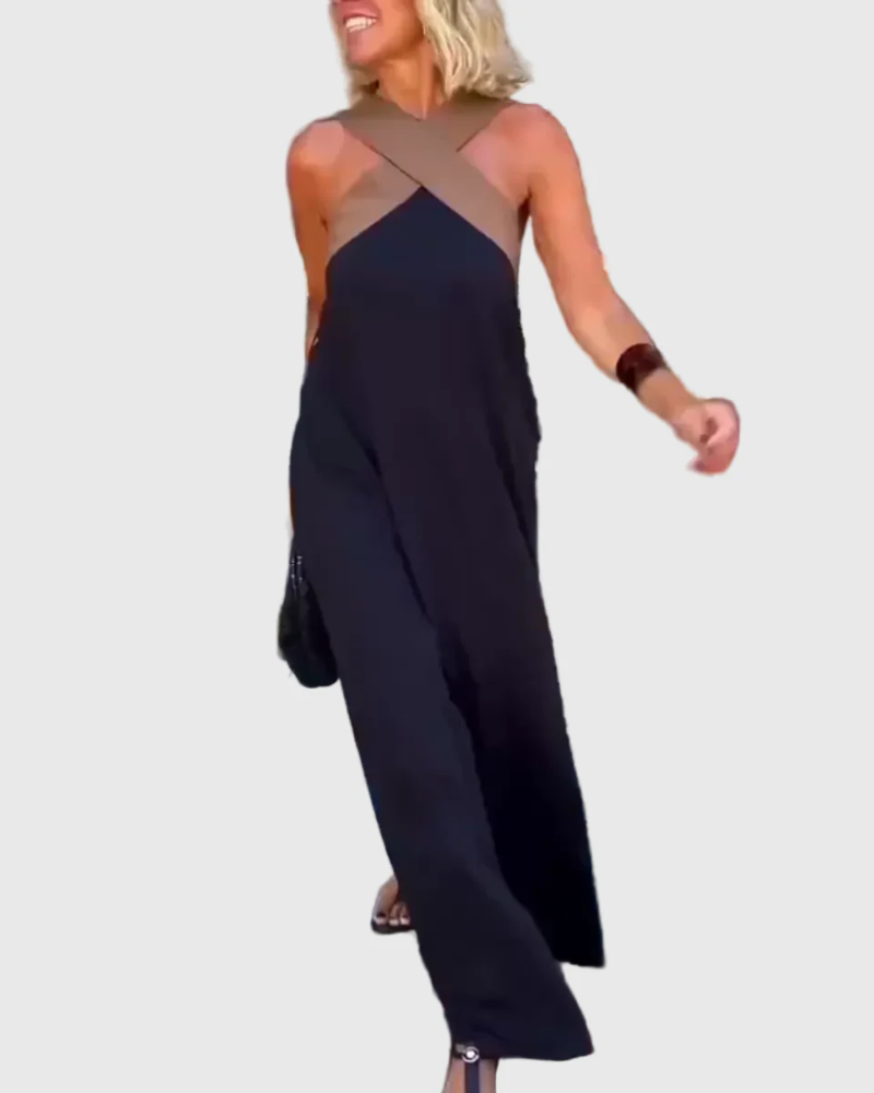 Woman wearing the Julie halterneck maxi dress in navy with a contrast crossover neckline, walking outdoors.