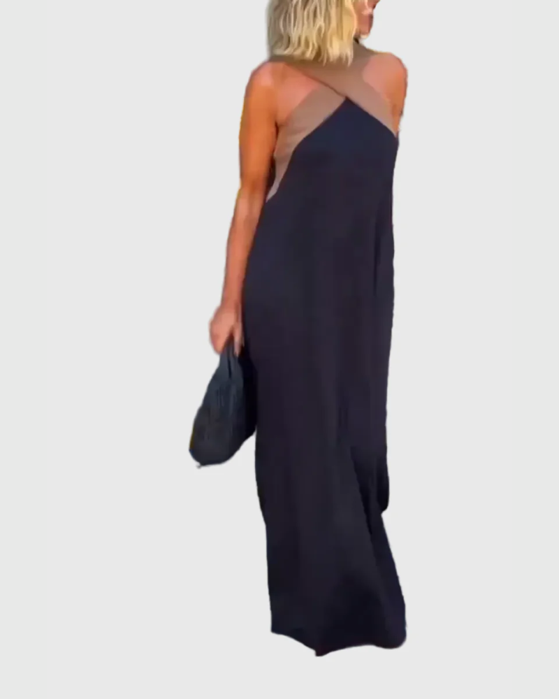 Woman wearing the Julie halterneck maxi dress in navy with a contrast crossover neckline, walking outdoors.