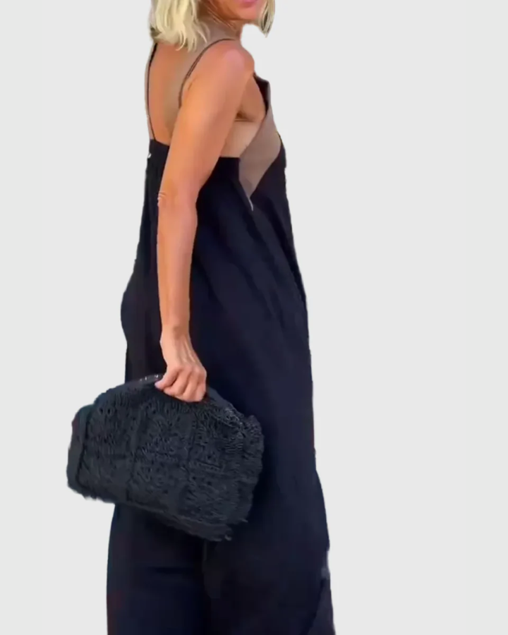 Woman wearing the Julie halterneck maxi dress in navy with a contrast crossover neckline, walking outdoors.