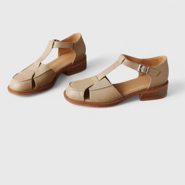 A woman wearing brown Mary Jane sandals with a T-strap and buckle, paired with a summer dress.