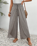 A woman wearing wide, flowing pants in a beige-and-black geometric print with an elastic drawstring waist.