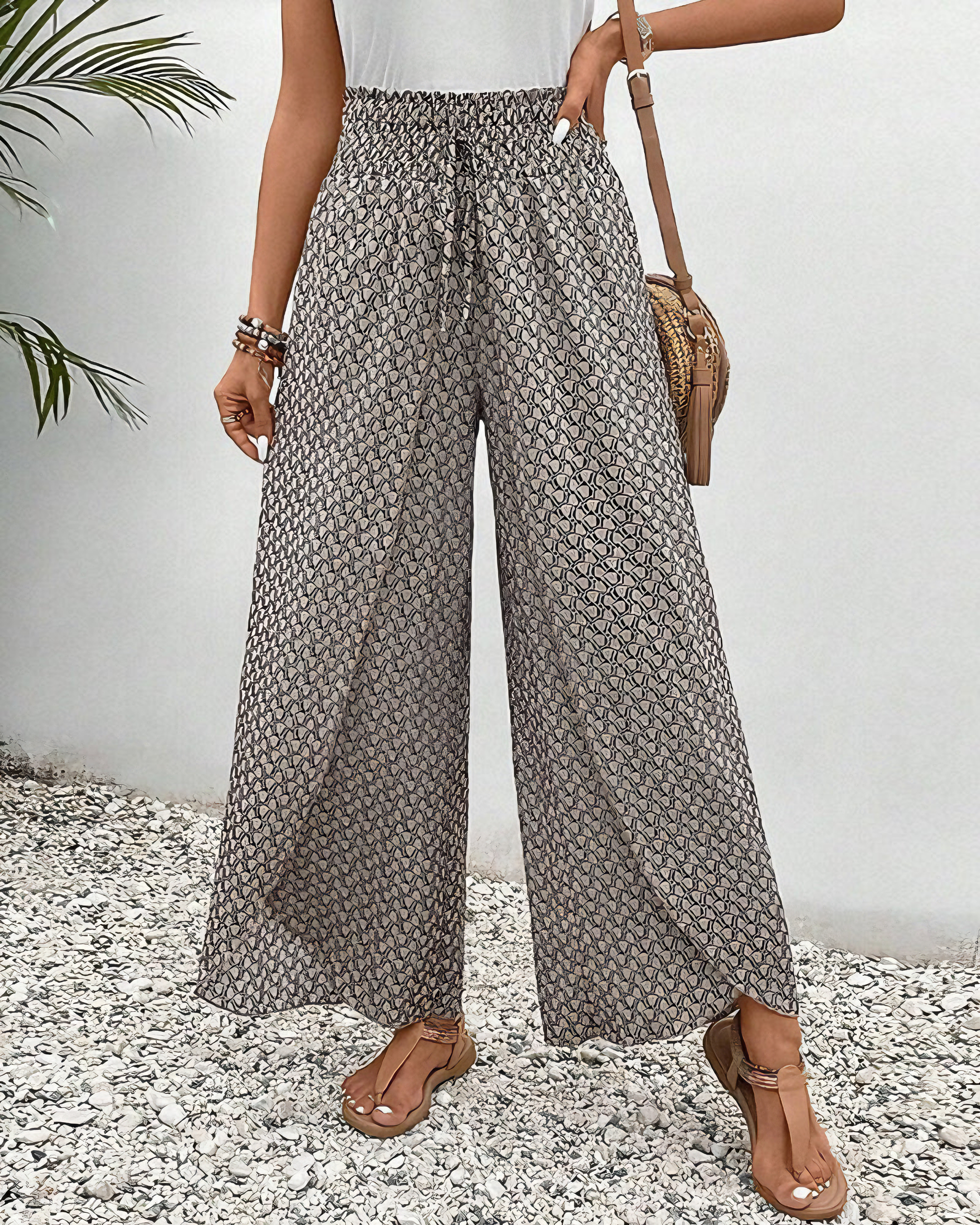 A woman wearing wide, flowing pants in a beige-and-black geometric print with an elastic drawstring waist.