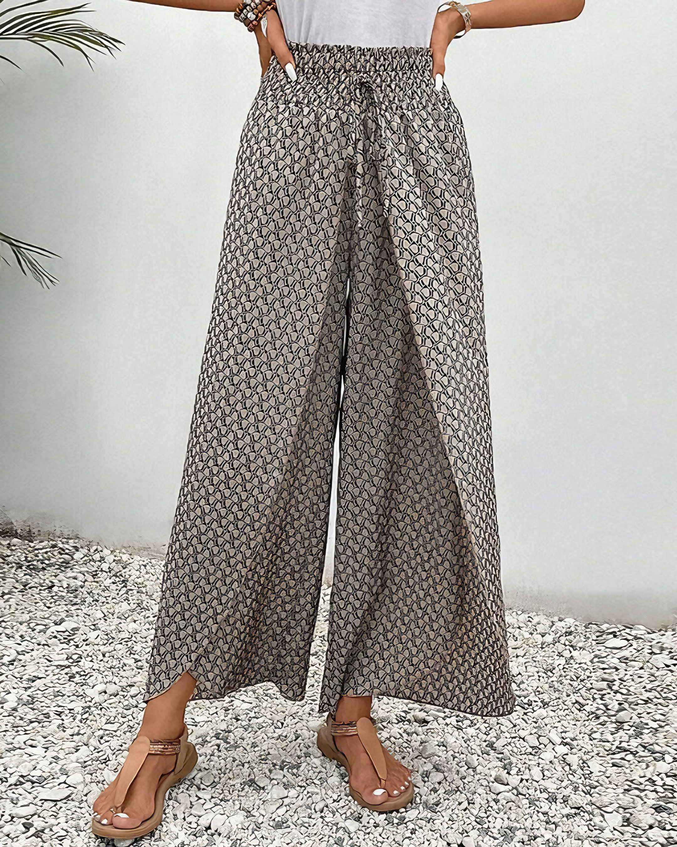 A woman wearing wide, flowing pants in a beige-and-black geometric print with an elastic drawstring waist.