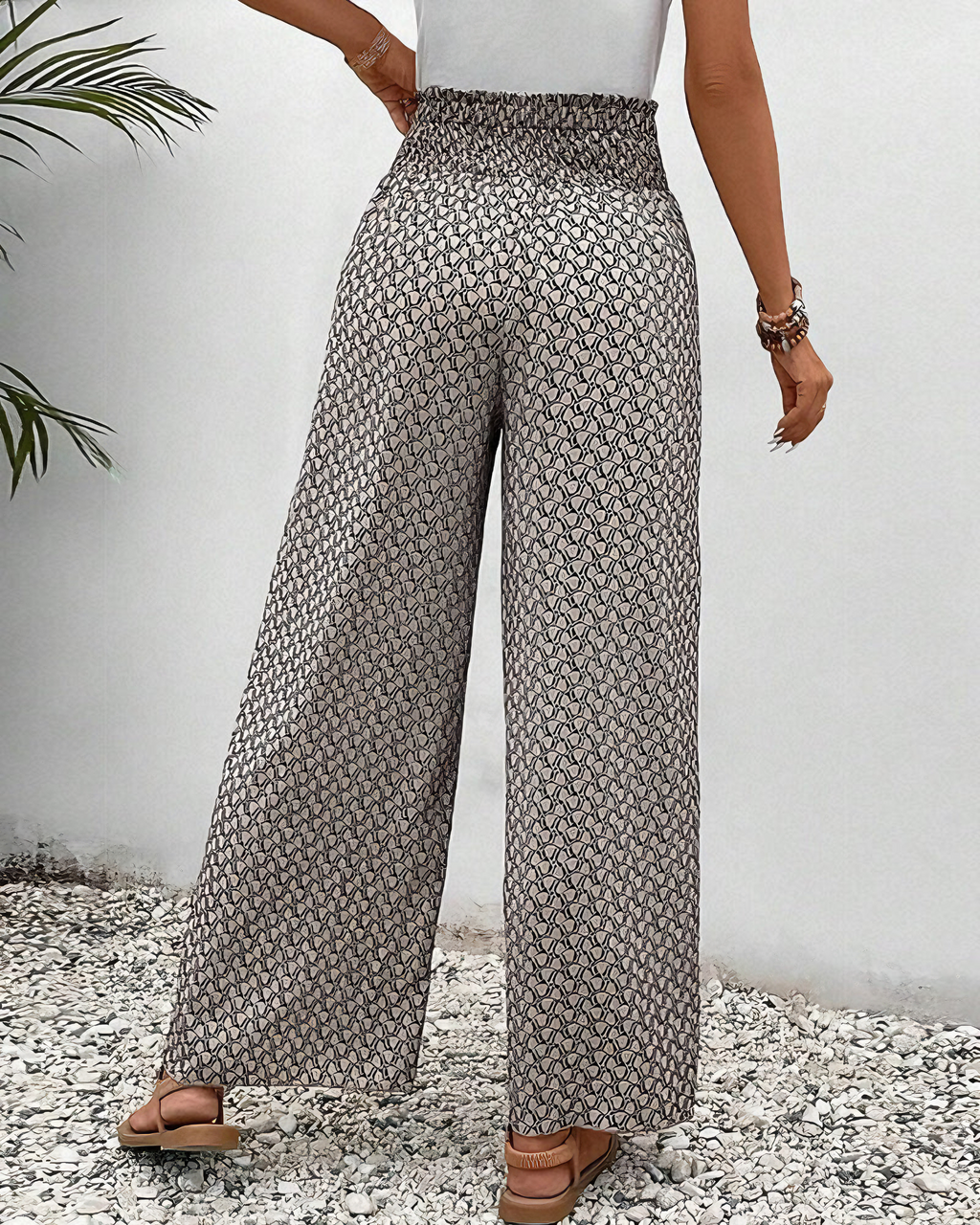 A woman wearing wide, flowing pants in a beige-and-black geometric print with an elastic drawstring waist.