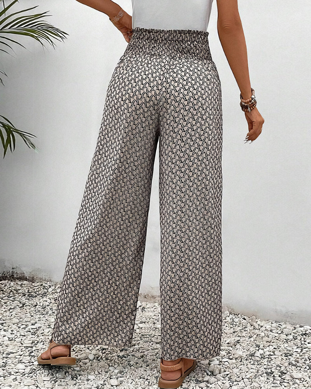 A woman wearing wide, flowing pants in a beige-and-black geometric print with an elastic drawstring waist.