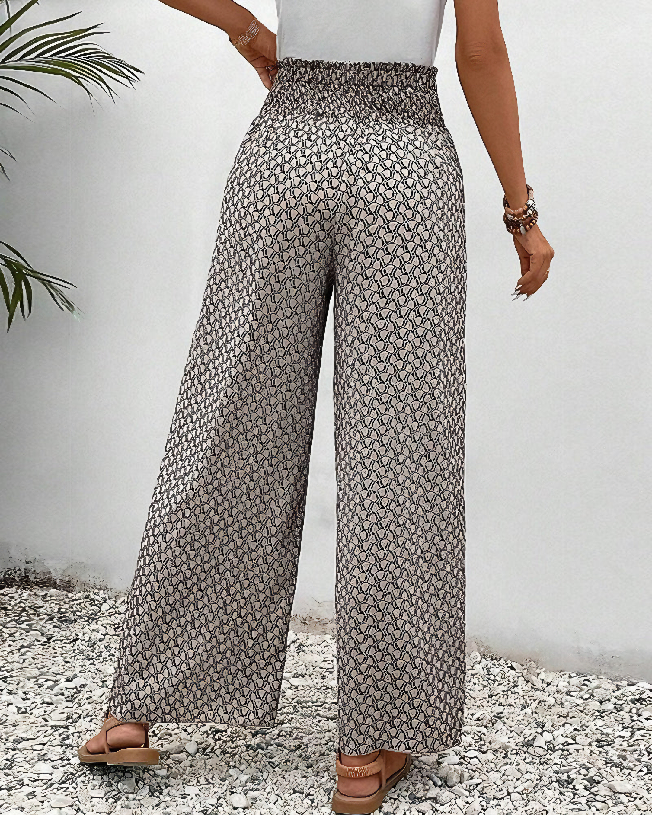 A woman wearing wide, flowing pants in a beige-and-black geometric print with an elastic drawstring waist.