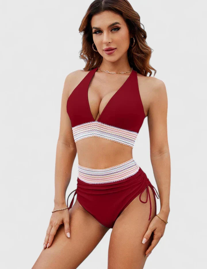 A woman wearing an elegant matching bikini set with a bold print, relaxed and confident on the beach.
