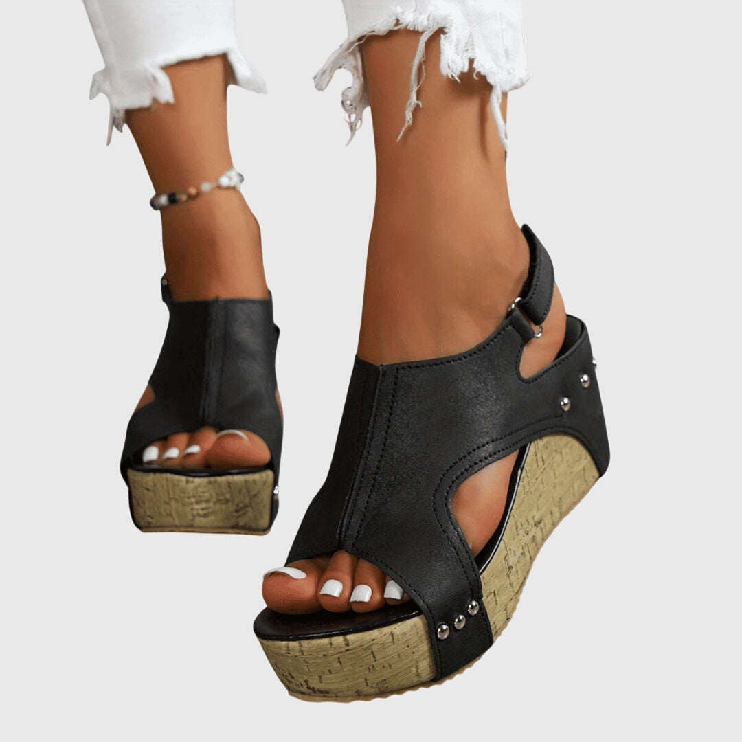 A woman in studded wedge sandals with an open front at a summer event.