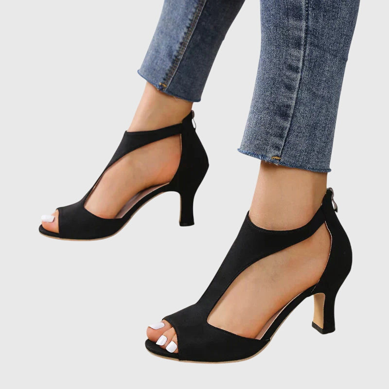 A woman wearing flexible orthopaedic heels, standing comfortably in a polished everyday outfit.