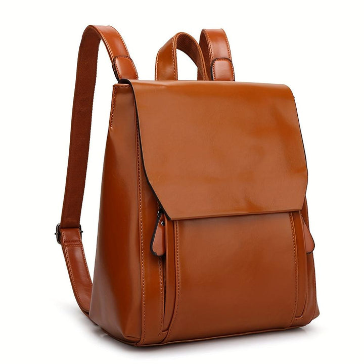 A woman wearing a padded vintage-style backpack over both shoulders while walking through the city.