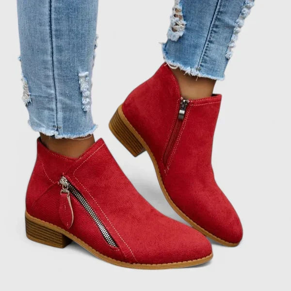 Woman wearing light blue vintage-style ankle boots, walking along a leafy street.