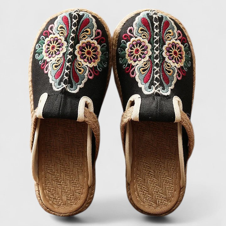 A woman wearing softly embroidered flat sandals, walking with ease on a sunny day.