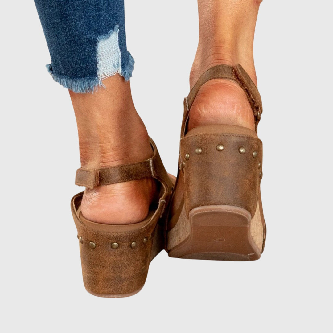 A woman in taupe wedge sandals with an open front, out shopping on a warm day.