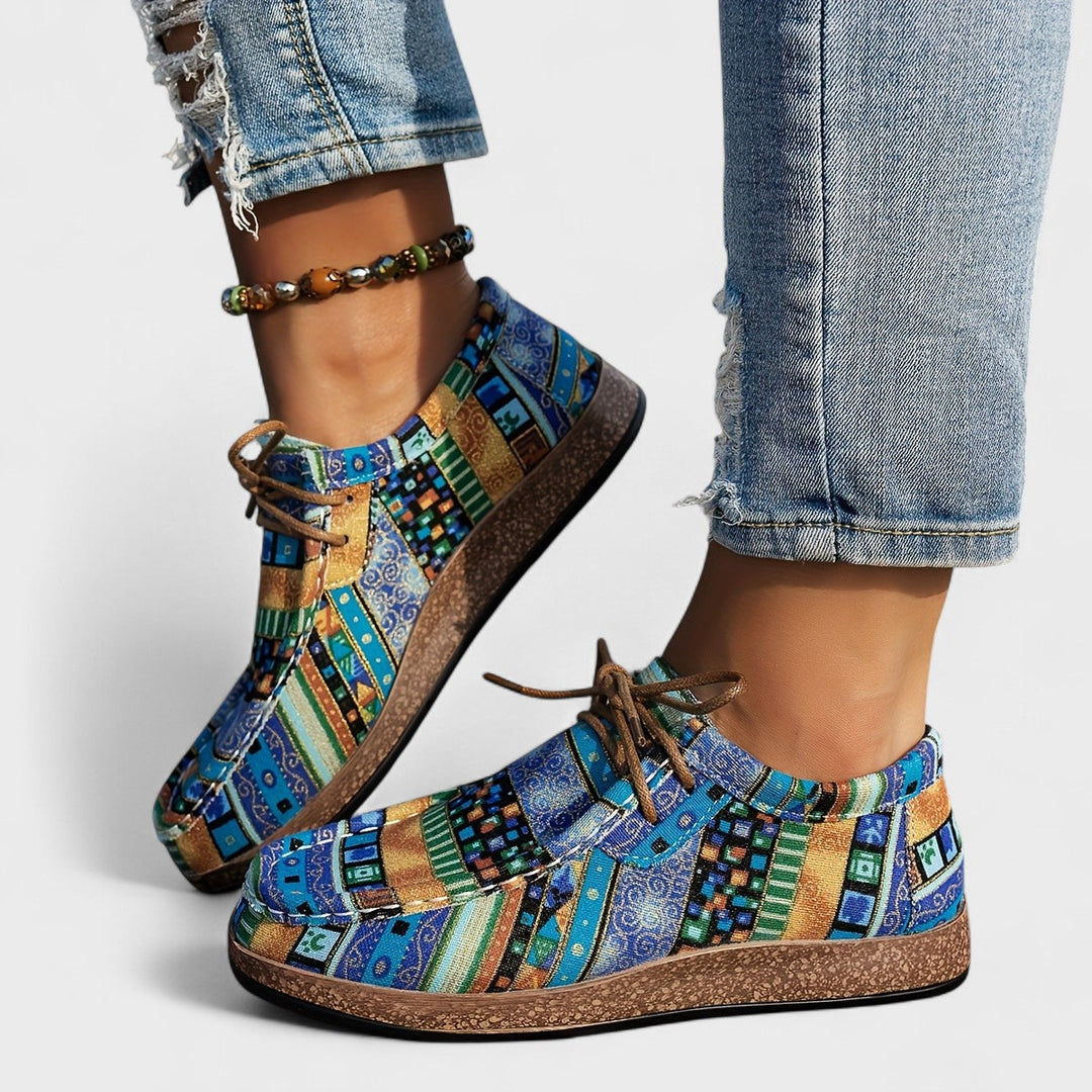 A woman wearing lace-up sneakers in a bold multicolour tribal print on a lightweight platform sole