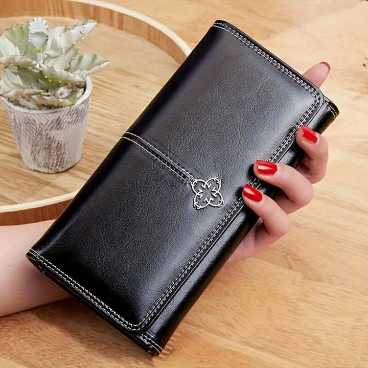 A woman holding a long flap-over wallet, tucking a card into its slot.