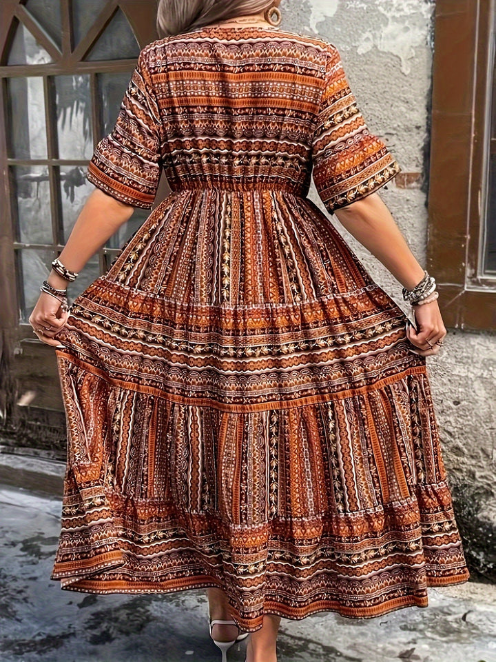 Woman wearing a flowing bohemian maxi dress with intricate pattern and ruffled details.
