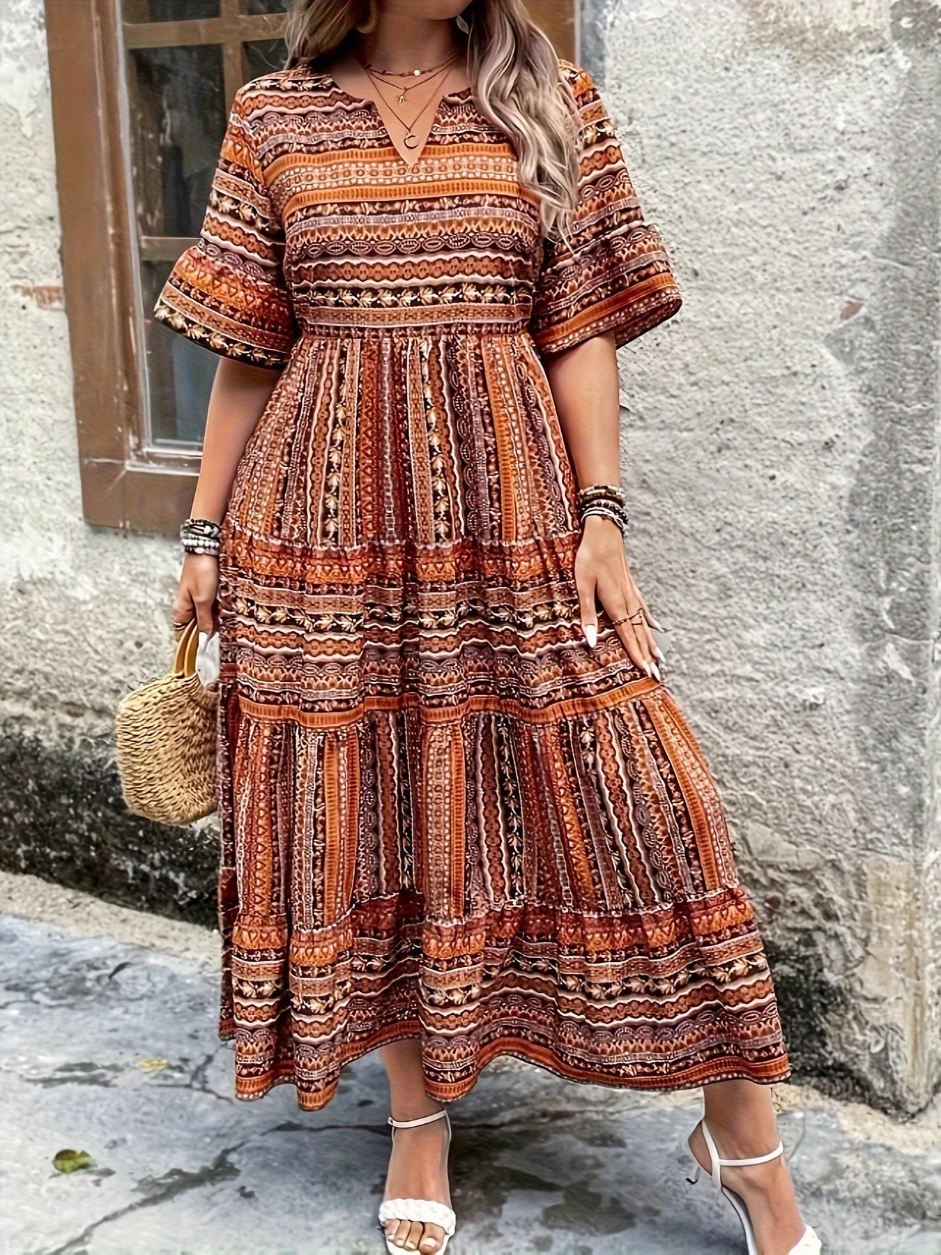 Woman wearing a flowing bohemian maxi dress with intricate pattern and ruffled details.