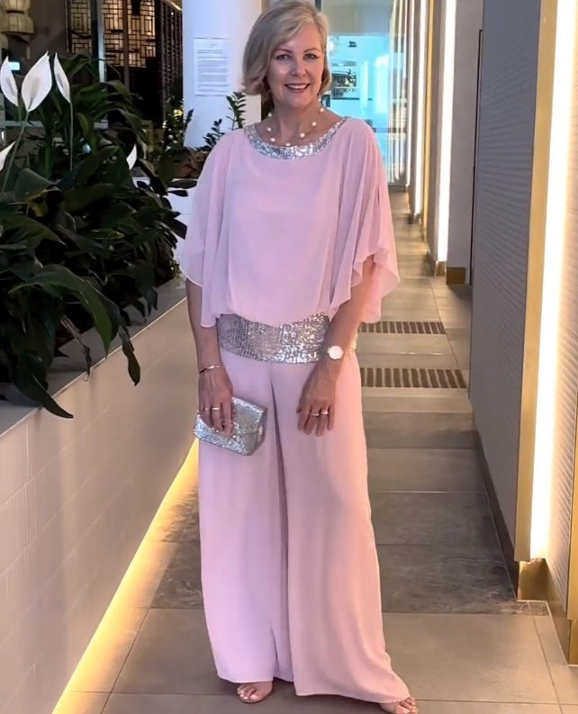 A woman wearing an embellished blouse-style top with softly flowing wide evening pants.