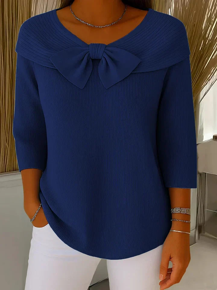 A woman wearing a shaped sweater with a soft bow detail, styled for a coffee date.