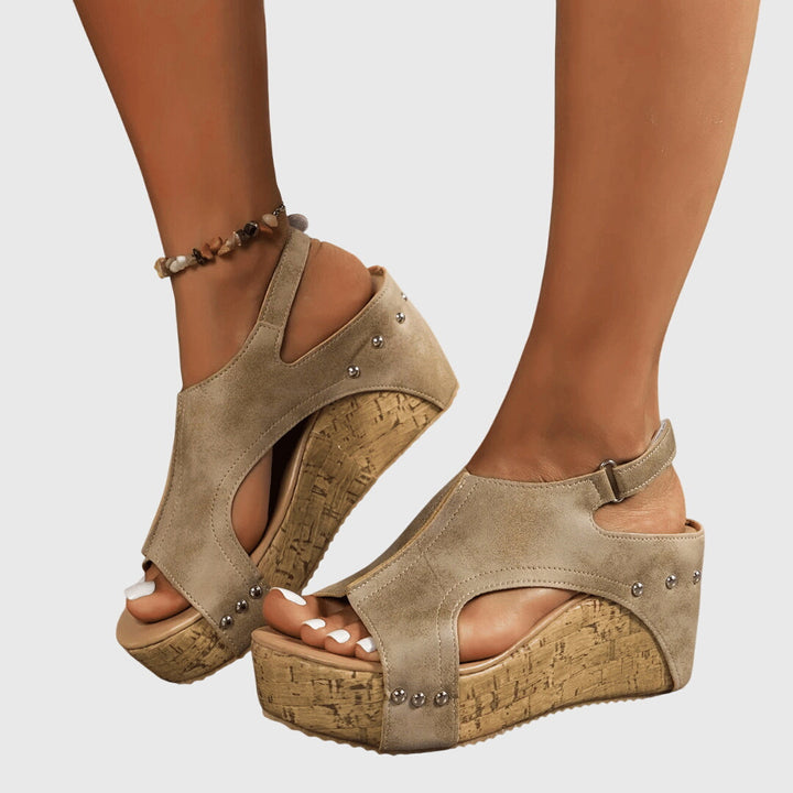 A woman in studded wedge sandals with an open front at a summer event.
