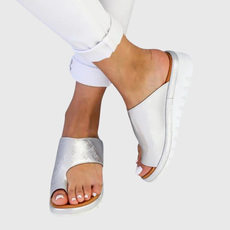 A woman in taupe toe-loop supportive sandals standing gracefully, feet cushioned and at ease.