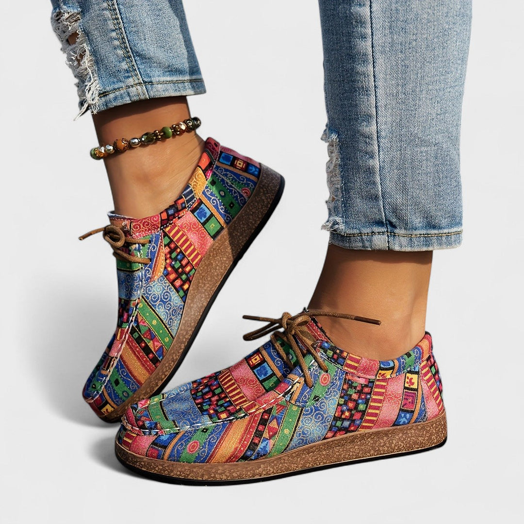 A woman wearing lace-up sneakers in a bold multicolour tribal print on a lightweight platform sole