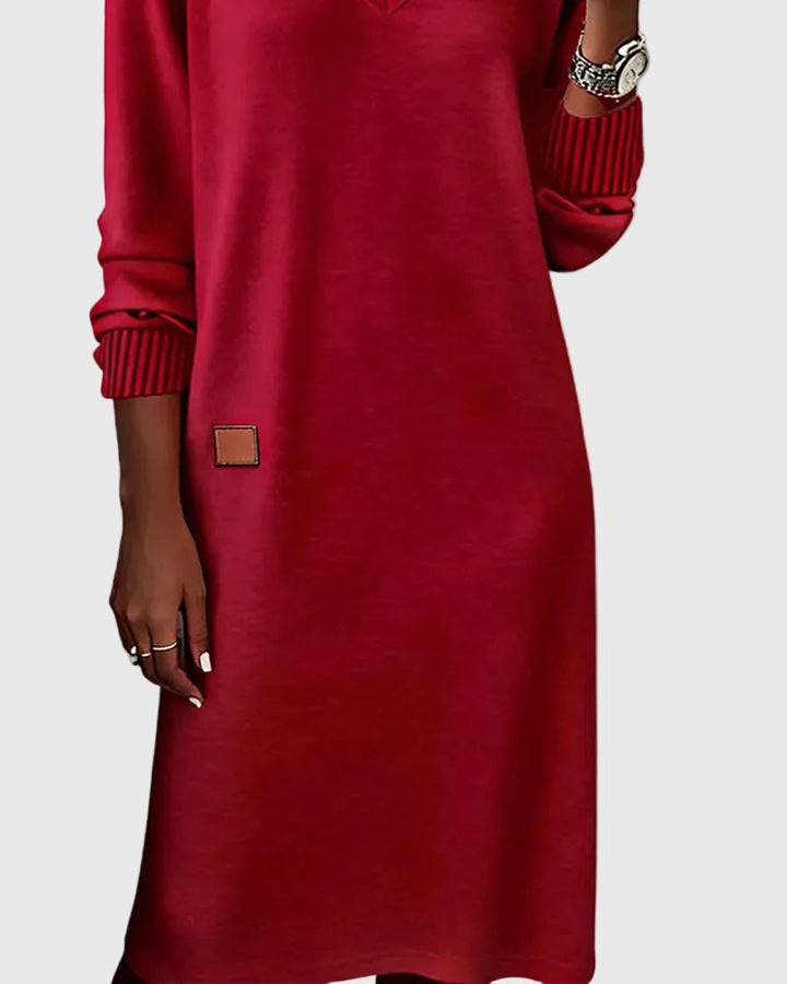 Woman wearing the Susan flowing elegant dress in beige, standing relaxed and smiling.