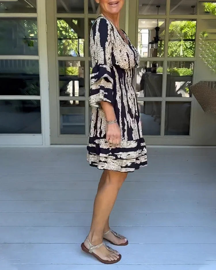 Woman wearing a boho print mini dress with ruffled sleeves and a soft V-neckline.