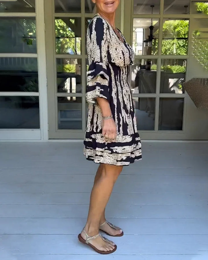 Woman wearing a boho print mini dress with ruffled sleeves and a soft V-neckline.