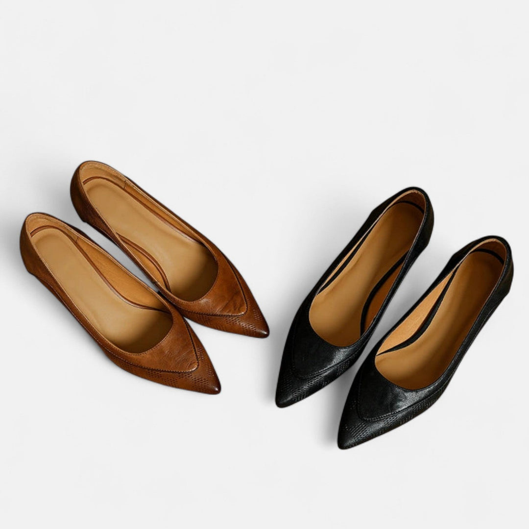 A woman wearing black pointed kitten-heel pumps with a subtle embossed finish.