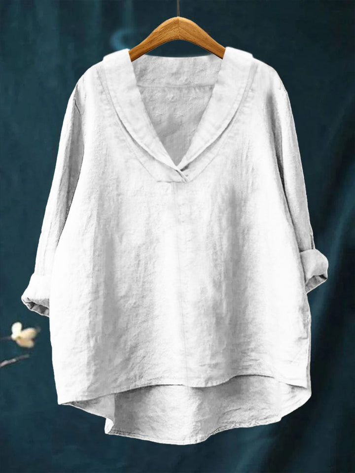 A woman wearing an elegant plain summer blouse with a flowing drape, styled with pants.