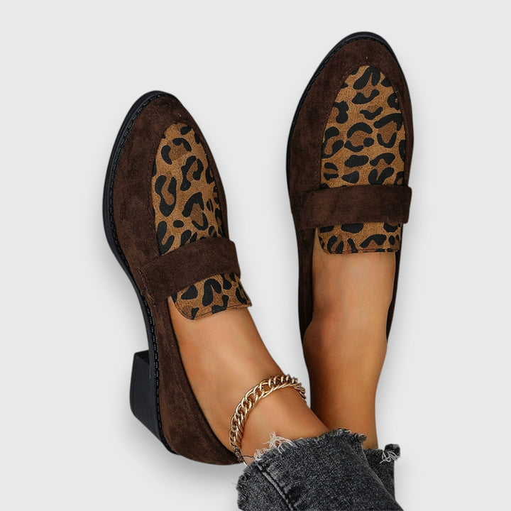 A woman wearing tan leopard print loafers with a low block heel, styled with jeans.