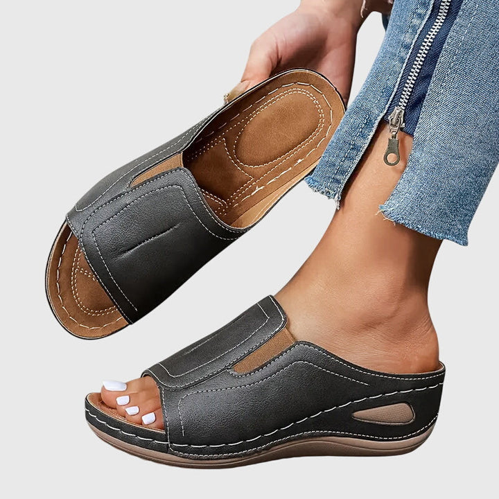 Tan open-toe wedge slides with a smooth one-piece upper and a cushioned wedge sole.