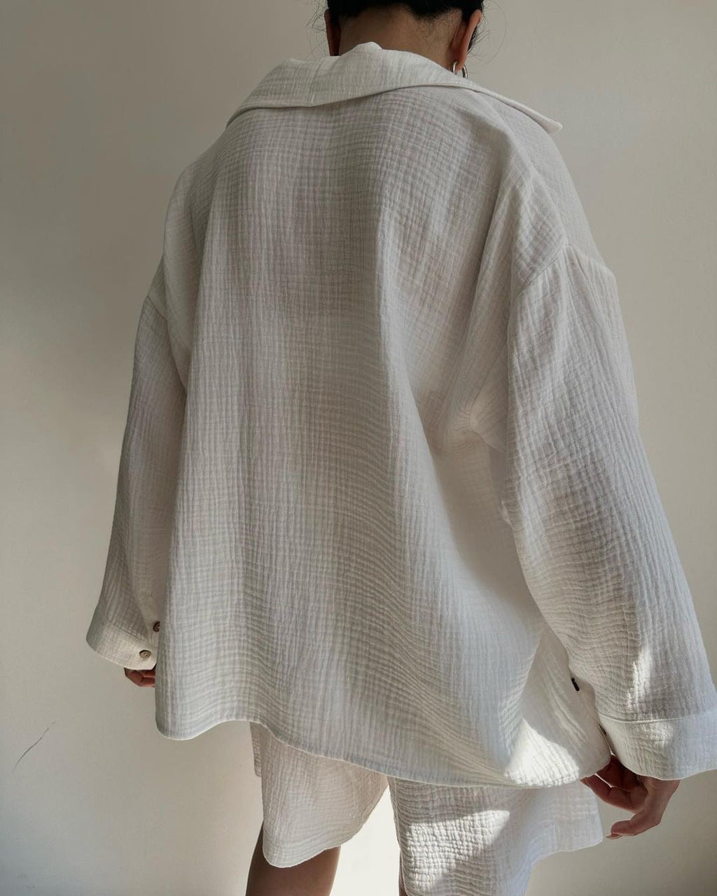 A woman wearing a flowing oversized shirt with drawstring shorts, relaxed and breezy.
