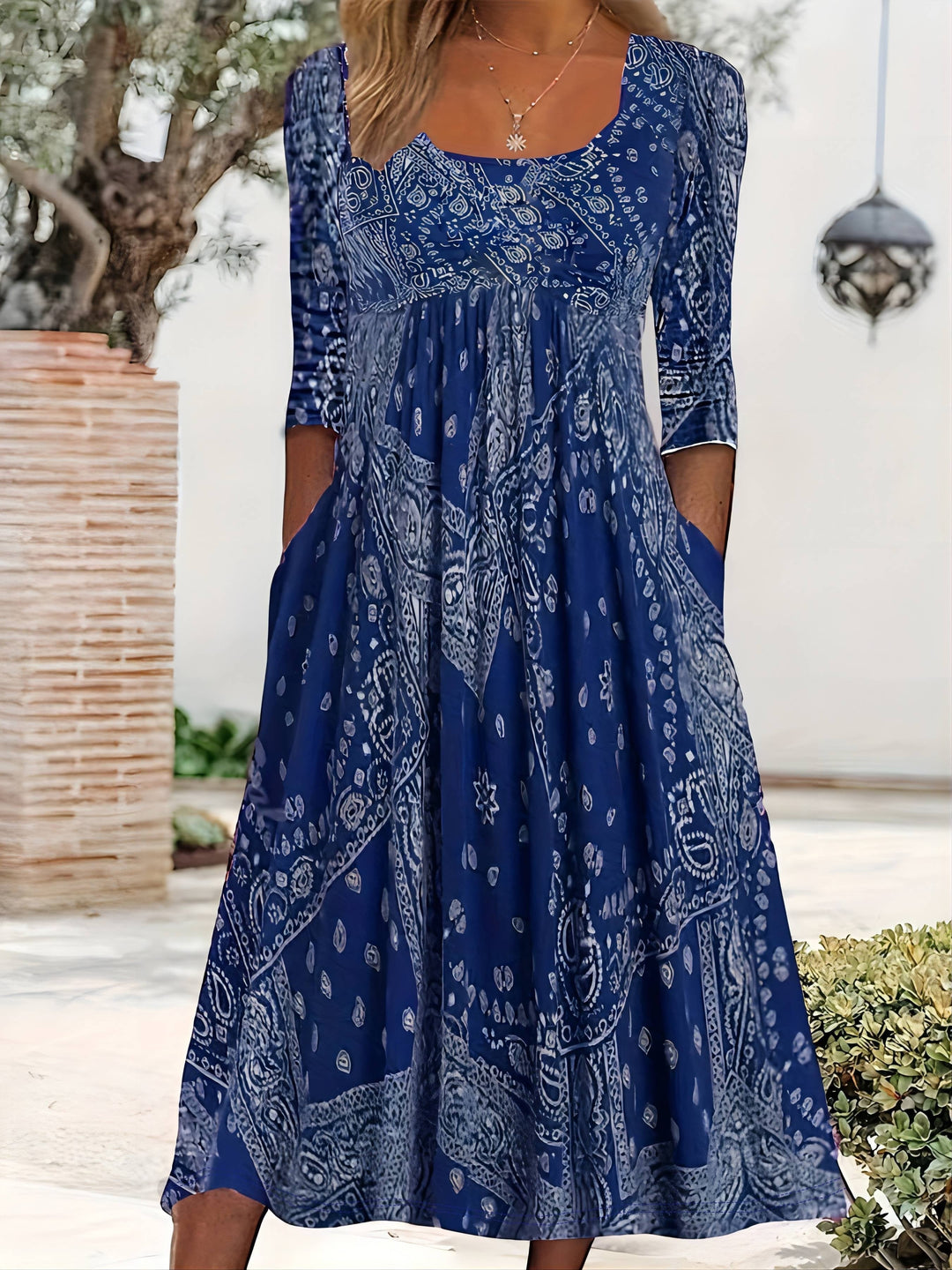 A woman wearing the Maria long sleeve grey paisley midi dress with a square neckline and flowing skirt, styled for a relaxed day out.