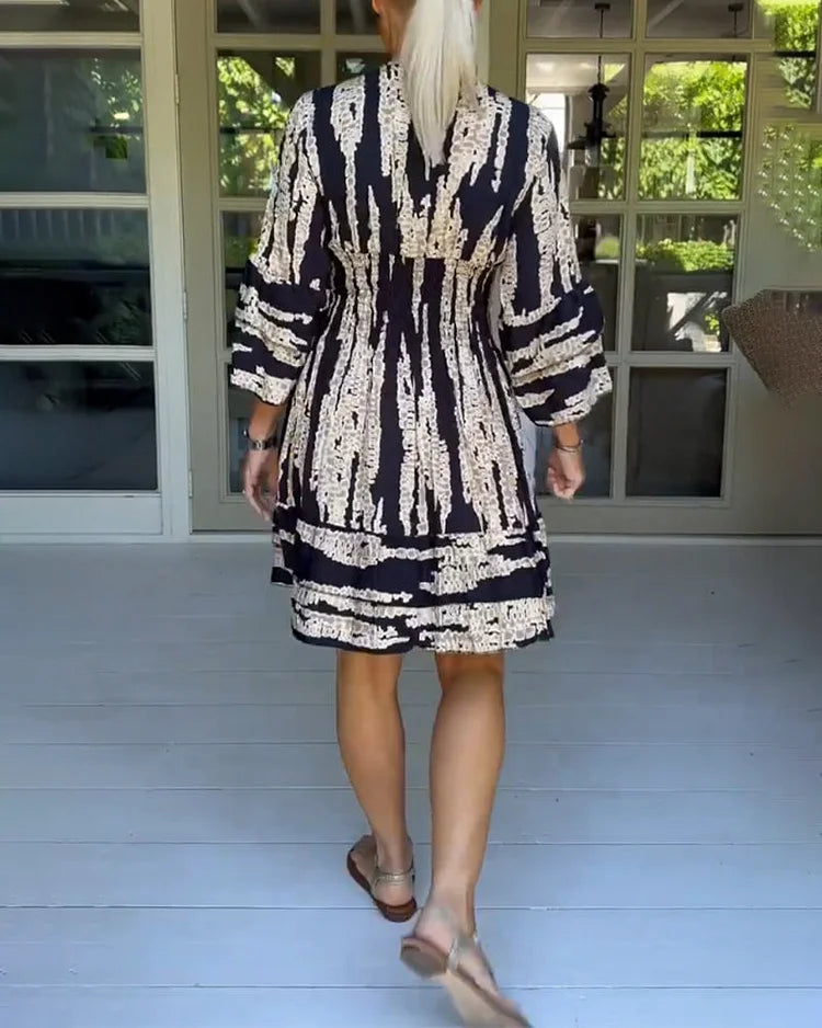 Woman wearing a boho print mini dress with ruffled sleeves and a soft V-neckline.
