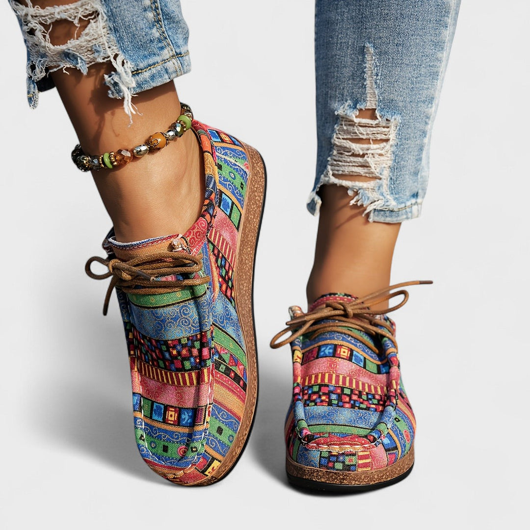 A woman wearing lace-up sneakers in a bold multicolour tribal print on a lightweight platform sole