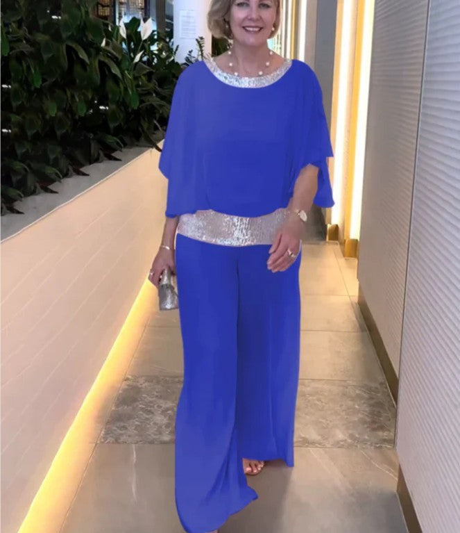 A woman wearing an embellished blouse-style top with softly flowing wide evening pants.
