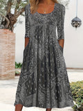 A woman wearing the Maria long sleeve grey paisley midi dress with a square neckline and flowing skirt, styled for a relaxed day out.