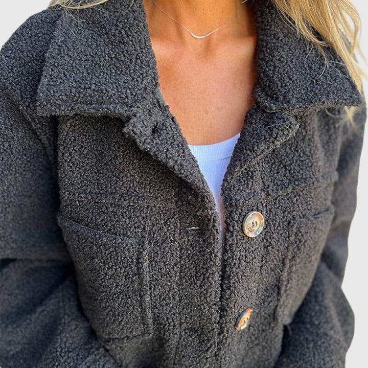 A woman wearing an elegant jacket with a button front over a simple outfit, looking polished.
